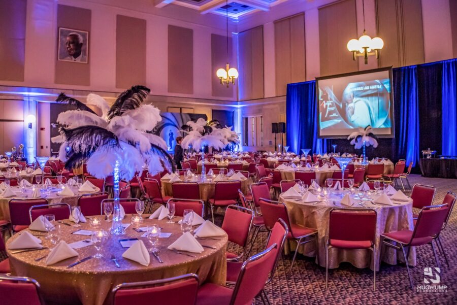 Tables and chairs set up with gold decor and feather centerpieces.