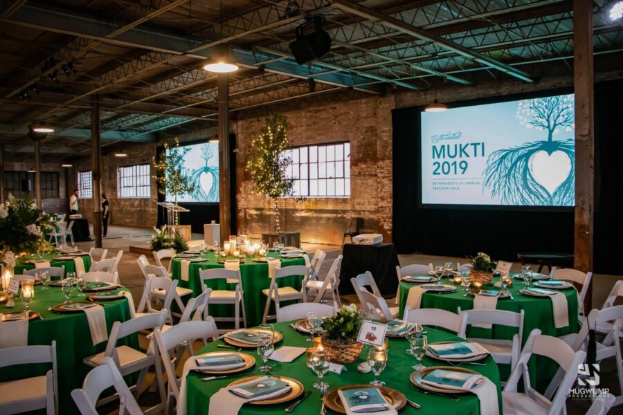 Room setup with chairs and tables for a corporate event with green and gold decorations