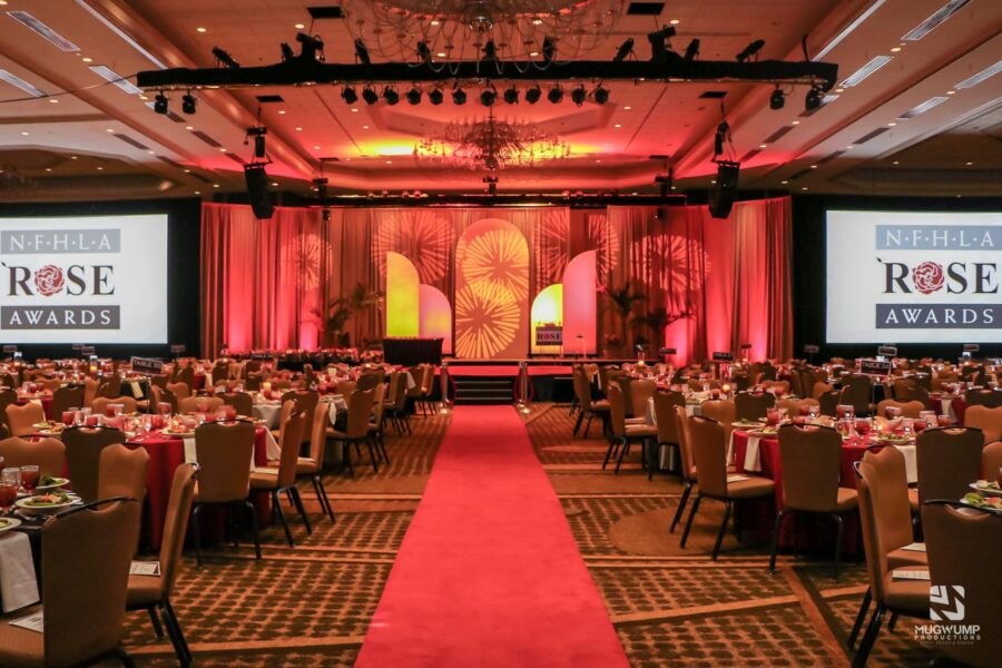 Room set up with chairs and tables for a corporate award gala with red lighting for decoration.
